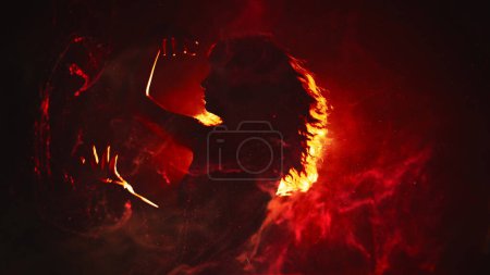 Photo for Ritual dance. Fire performance. Mysterious woman moving in red flame swirls bright yellow orange projector light on dark background copy space. - Royalty Free Image