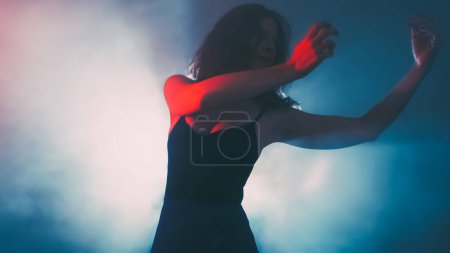 Photo for Modern ballet performance. Inspiration dance. Feminine graceful flexible woman moving in haze shadow neon projector spot light dark background copy space. - Royalty Free Image