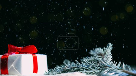 Téléchargez les photos : Vacances d'hiver. Cadeau de Noël. Décoration festive. Coffret cadeau en papier blanc ruban rouge scotché sur branche de pin félicitations neigeuses publicité bokeh lumières fond espace libre. - en image libre de droit