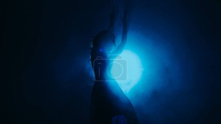 Photo for Choreography performance. Dancer show. Professional artistic woman moving in blue mist shadow in bright projector light on dark background copy space. - Royalty Free Image