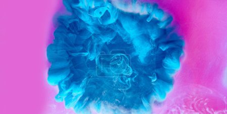 Téléchargez les photos : Fond nuage d'encre. Explosion hypnotique. Débit de goutte de peinture bleue dans de l'eau rose abstraite mystérieuse vapeur liquide éthéré propagation dans l'art dynamique vibrant. - en image libre de droit
