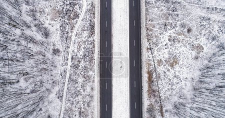 Photo for Aerial snowy road. Winter landscape. White frozen forest tree crowns with asphalted track cloudy day countryside driveway pavement. - Royalty Free Image