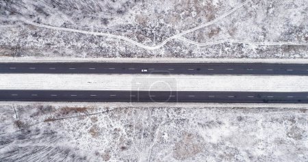 Photo for Aerial snowy view. Countryside winter road. White frozen fields with asphalted track traffic driveway cloudy day cold season drone. - Royalty Free Image