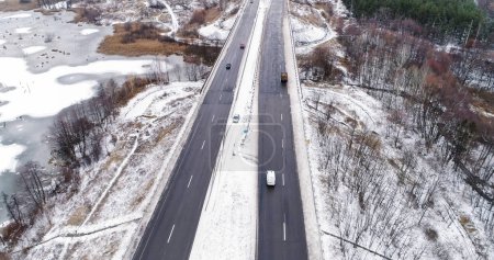 Photo for Aerial winter view. Countryside snowy road. White frozen lake and forest near asphalted track traffic driveway cloudy day cold season drone. - Royalty Free Image