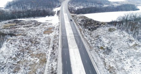 Photo for Drone winter view. Snowy road pavement. Beautiful white frozen earth forest trees field lake asphalted track traffic cloudy day. - Royalty Free Image