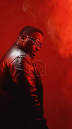 Photo for Color light portrait. Neon people. Profile of man in leather jacket and party goggles enjoying night life isolated on red smoke free space background. - Royalty Free Image