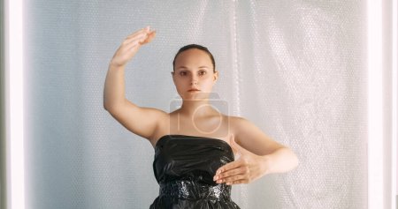 Photo for Mind control. Social manipulation. Propaganda brainwashing. Hypnotized passive marionette doll woman in black plastic bag dress on bubble wrap background. - Royalty Free Image