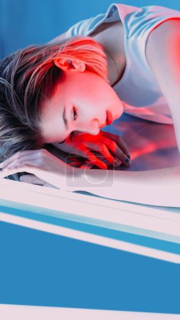 Photo for Cyberpunk fashion. Futuristic generation. Young beautiful stylish model woman face portrait with neon laser LED lamps on blue background copy space. - Royalty Free Image
