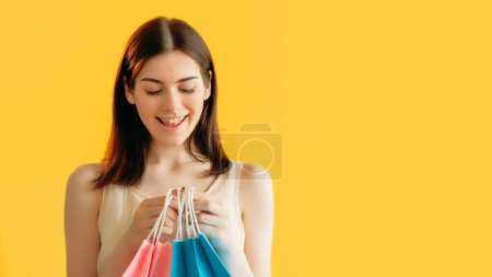 Photo for Happy purchase. Shopping discount. Black Friday. Pleased woman customer with desired pink blue paper bags isolated on orange background empty space. - Royalty Free Image