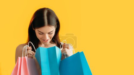 Photo for Shopping bonus. Customer discount. Satisfied woman buyer with paper bags enjoying wish gifts purchase isolated on orange background empty space. - Royalty Free Image