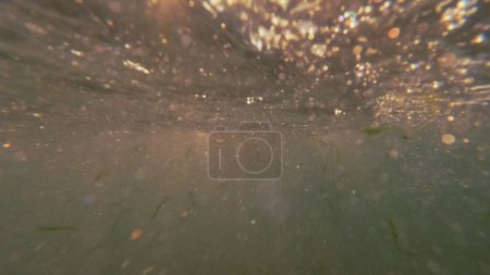Foto de Superficie submarina. Textura marina. Luz solar con burbujas que suben al océano abstracto líquido marino gotas espacio vacío fondo. - Imagen libre de derechos