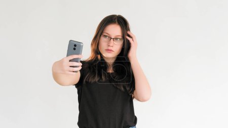 Photo for Selfie shooting. Social media. Blogger lifestyle. Confident woman posing taking picture on mobile phone camera isolated on white empty space background. - Royalty Free Image