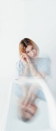 Photo for Emotional disorder. Psychology problem. Pensive young woman at blur mirror reflection feeling inner conflict on white background empty space. - Royalty Free Image
