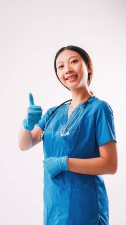 Photo for Healthcare specialist. Clinic services. Confident happy doctor woman in blue professional uniform gloves stethoscope with thumb up hand gesture isolated on white background. - Royalty Free Image