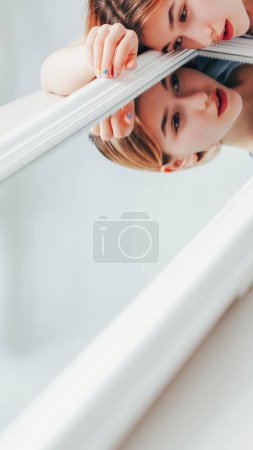 Reflection love. Self acceptance. Mental wellbeing. Young beautiful confident woman enjoying attractive face appearance in white mirror copy space.