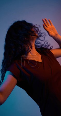 Photo for Elegance moving. Inspire dancing. Color light unrecognizable delicate exquisite brunette woman enjoying atmosphere on blue background. - Royalty Free Image