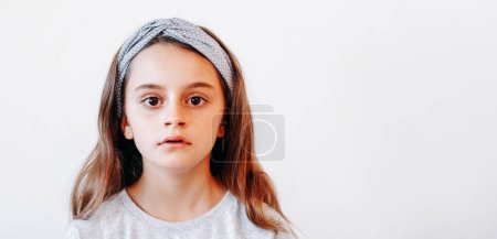 Surprised kid. Child staring. Attentive astonished little girl in hair band looking with concentrated expression isolated on white empty space background.