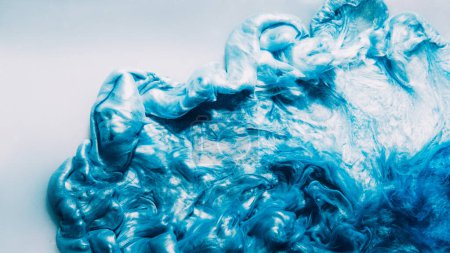 Photo for Ink drop. Glitter fluid. Smoke cloud. Blue color glowing shimmering liquid paint blob spreading in water on light abstract art background. - Royalty Free Image