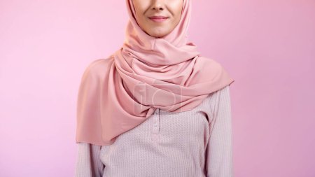 Téléchargez les photos : La mode musulmane. Accessoire foulard. Portrait de femme souriante heureuse confiante méconnaissable portant hijab rose isolé sur fond d'espace vide de couleur pastel. - en image libre de droit