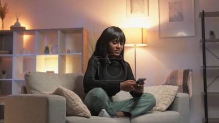 Photo for Negative chat. Mobile fraud. Network problem. Confused dissatisfied woman using phone app sitting home interior. - Royalty Free Image