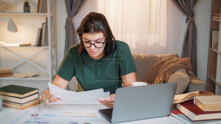 Téléchargez les photos : Analytique des données. Chargé de compte. Femme travailleuse occupée analysant les graphiques du marché sur le lieu de travail à domicile du bureau d'ordinateur portable. - en image libre de droit