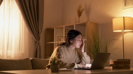 Photo for Learning fatigue. Tired woman. Remote course. Exhausted lady watching online lesson on laptop at dark room workplace interior. - Royalty Free Image