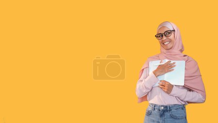 Photo for Writer inspiration. Smart people. Intelligent enthusiastic smiling woman in hijab glasses with pen journal book for notes isolated on yellow empty space background. - Royalty Free Image