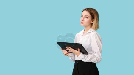 Female executive. Career planning. Digital technology. Minding ideas. Work promotion. Pensive dreamy woman holding tablet isolated on blue empty space.