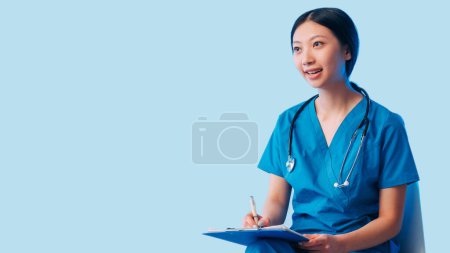 Ärztliche Beratung. Gesundheitsuntersuchung. Glückliche Ärztin in Uniform sitzt im Gespräch zuhörende Patientin schreibt Notizen Diagnose isoliert auf blauem leeren Raum Hintergrund.