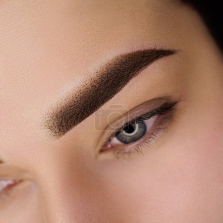 Permanent eyebrow makeup in the powder technique. Close-up eyebrow tattooing gentle eyebrow contouring in permanent makeup.