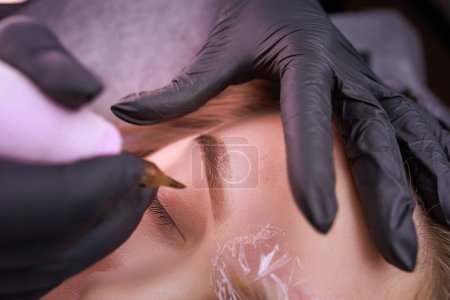 Photo for The process of performing permanent eyebrow makeup with a tattoo machine. PMU Procedure, Permanent Eyebrow Makeup. - Royalty Free Image