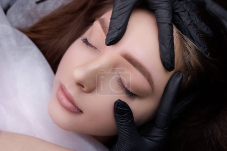 Photo for Close-up demonstration of permanent makeup after eyebrow design procedure. PMU Procedure, Permanent Eyebrow Makeup. - Royalty Free Image