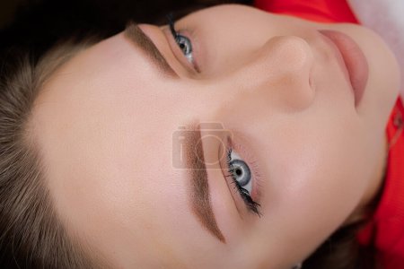 Beautiful girl with blue eyes poses after permanent eyebrow makeup. PMU Procedure, Permanent Eyebrow Makeup.