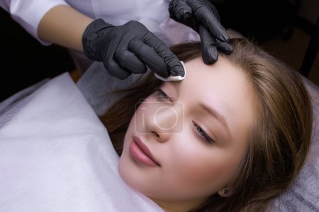 Preparation of the model's eyebrows for the procedure of permanent makeup. PMU Procedure, Permanent Eyebrow Makeup.