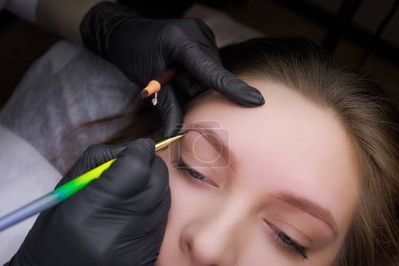 Photo for Application of markings on the eyebrows before the procedure of permanent makeup. PMU Procedure, Permanent Eyebrow Makeup. - Royalty Free Image