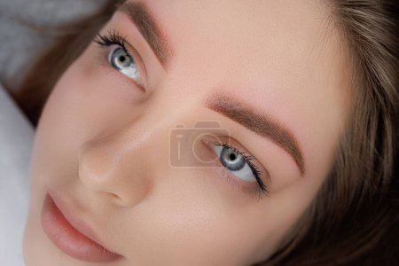 Photo for A young girl poses in front of the camera after completing a permanent eyebrow makeup procedure. PMU Procedure, Permanent Eyebrow Makeup. - Royalty Free Image