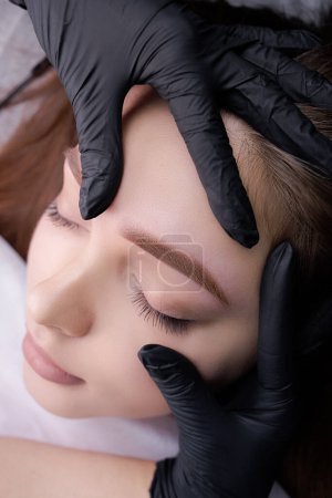 Photo for Close-up demonstration of permanent makeup after eyebrow design procedure. PMU Procedure, Permanent Eyebrow Makeup. - Royalty Free Image