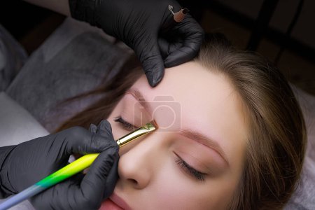 Photo for Using a brush, the master applies marking lines on the model's eyebrows before permanent eyebrow makeup. PMU Procedure, Permanent Eyebrow Makeup. - Royalty Free Image
