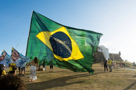 Foto de Salvador, Bahia, Brasil - 22 de octubre de 2022: Partidarios del presidente de Brasil, Jair Bolsonaro, colocan una gran bandera brasileña en la plaza Farol da Barra en Salvador, Bahia. - Imagen libre de derechos