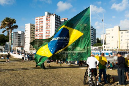Foto de Salvador, Bahia, Brasil - 22 de octubre de 2022: Partidarios del presidente de Brasil, Jair Bolsonaro, protestan colocando una gran bandera brasileña en la plaza Farol da Barra en Salvador. - Imagen libre de derechos