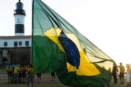 Foto de Salvador, Bahia, Brasil - 22 de octubre de 2022: Partidarios del presidente de Brasil, Jair Bolsonaro, colocan una gran bandera brasileña en la plaza Farol da Barra en Salvador, Bahia. - Imagen libre de derechos