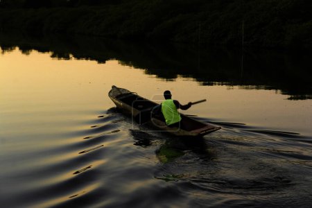 Téléchargez les photos : Aratuipe, Bahia, Brésil - Le 31 août 2018 : Un pêcheur pagayant sur la rivière Jaguaripe, ville d'Aratuipe, au coucher du soleil. - en image libre de droit