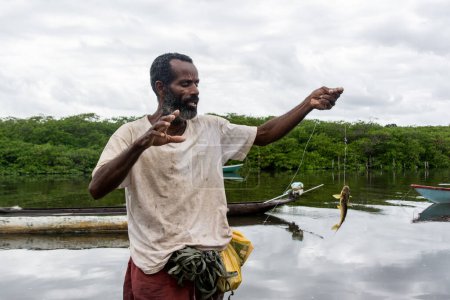 Téléchargez les photos : Aratuipe, Bahia, Brésil - 31 août 2018 : Pêcheur tenant une ligne de pêche avec du poisson à l'hameçon. Ville d'Aratuipe, Bahia, Brésil. - en image libre de droit