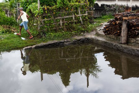 Téléchargez les photos : Aratuipe, Bahia, Brésil - 31 août 2018 : Réflexion d'un homme dans l'eau de la rivière. Il passe par le sommet. Ville d'Aratuipe, Bahia, Brésil. - en image libre de droit