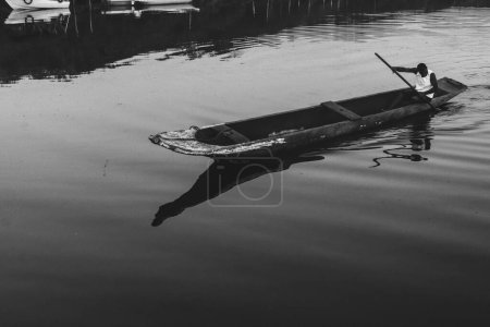 Téléchargez les photos : Aratuipe, Bahia, Brésil - 31 août 2018 : Photographie en noir et blanc d'un pêcheur pagayant sur la rivière Jaguaripe, ville d'Aratuipe, en fin d'après-midi. - en image libre de droit