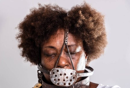Photo for Face portrait of black woman with iron mask of slavery covering her mouth. Studio reproduction. - Royalty Free Image