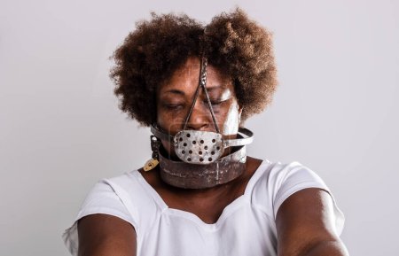 Photo for Face portrait of black woman with iron mask of slavery covering her mouth. Studio reproduction. - Royalty Free Image