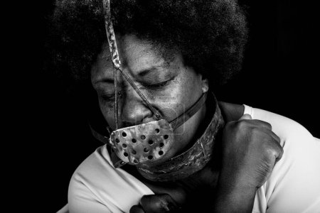 Photo for Black woman in chains with an iron mask on her face, representing the slave Anastacia. Pain and suffering, torture. Slavery in Brazil. - Royalty Free Image