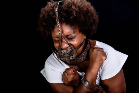 Schwarze Frau in Ketten mit eiserner Maske im Gesicht, die die Sklavin Anastacia darstellt. Schmerz und Leid, Folter. Sklaverei in Brasilien.