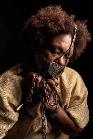 Retrato de una mujer negra con cadenas en las manos y una máscara de hierro en la cara. Representación del esclavo Anastacia. Esclavitud en Brasil.
